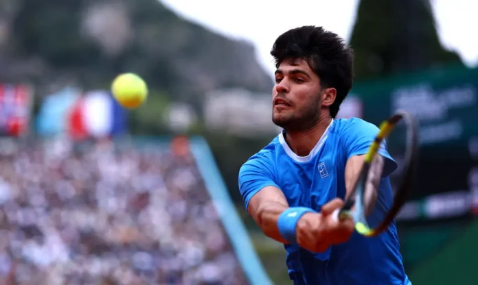 Com isso, ele também ficará fora do Masters de Roma e encerrará antecipadamente sua temporada europeia no saibro. Atual campeão do torneio francês, Alcaraz buscava o terceiro título consecutivo em Paris. No entanto, após novos exames médicos, decidiu priorizar a recuperação física e evitar agravamento da lesão. Lesão começou no Aberto de Barcelona O problema surgiu durante a primeira rodada do ATP 500 de Barcelona, no início de abril. Mesmo após vencer a partida, o espanhol sentiu fortes dores e acabou abandonando o torneio. Inicialmente, a equipe acreditava que a lesão seria menos grave. Porém, exames posteriores mostraram um quadro mais delicado, o que levou também à desistência do Masters de Madri e, agora, de Roma e Roland Garros. Alcaraz diz que momento é difícil Nas redes sociais, Alcaraz explicou que a decisão foi tomada com cautela e pensando no longo prazo. Segundo ele, o objetivo agora é acompanhar a evolução da recuperação antes de definir a data de retorno às quadras. “Este é um momento difícil para mim, mas tenho certeza de que sairemos mais fortes”, afirmou o tenista ao comunicar sua ausência dos principais torneios do saibro. Ausência abre caminho para novos favoritos Sem Alcaraz, o cenário de Roland Garros muda completamente. O espanhol era um dos principais favoritos ao título e defendia 2 mil pontos no ranking da ATP. Além disso, sua ausência fortalece ainda mais a candidatura do italiano Jannik Sinner, atual número 1 do mundo, que agora surge como um dos principais nomes na disputa pelo Grand Slam francês. Foco agora está em Wimbledon Mesmo fora de toda a temporada de saibro, Alcaraz mantém o foco em retornar para Wimbledon Championships, previsto para junho. A última vez que o espanhol ficou fora de um torneio importante havia sido no Aberto da Austrália de 2023, quando sofreu uma lesão na perna. Agora, o desafio será recuperar o punho a tempo de voltar em alto nível para a sequência da temporada.